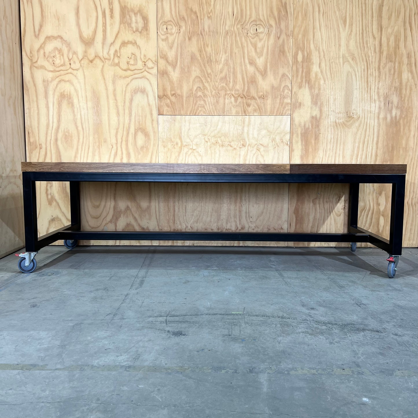 Timber table on black metal frame with castors