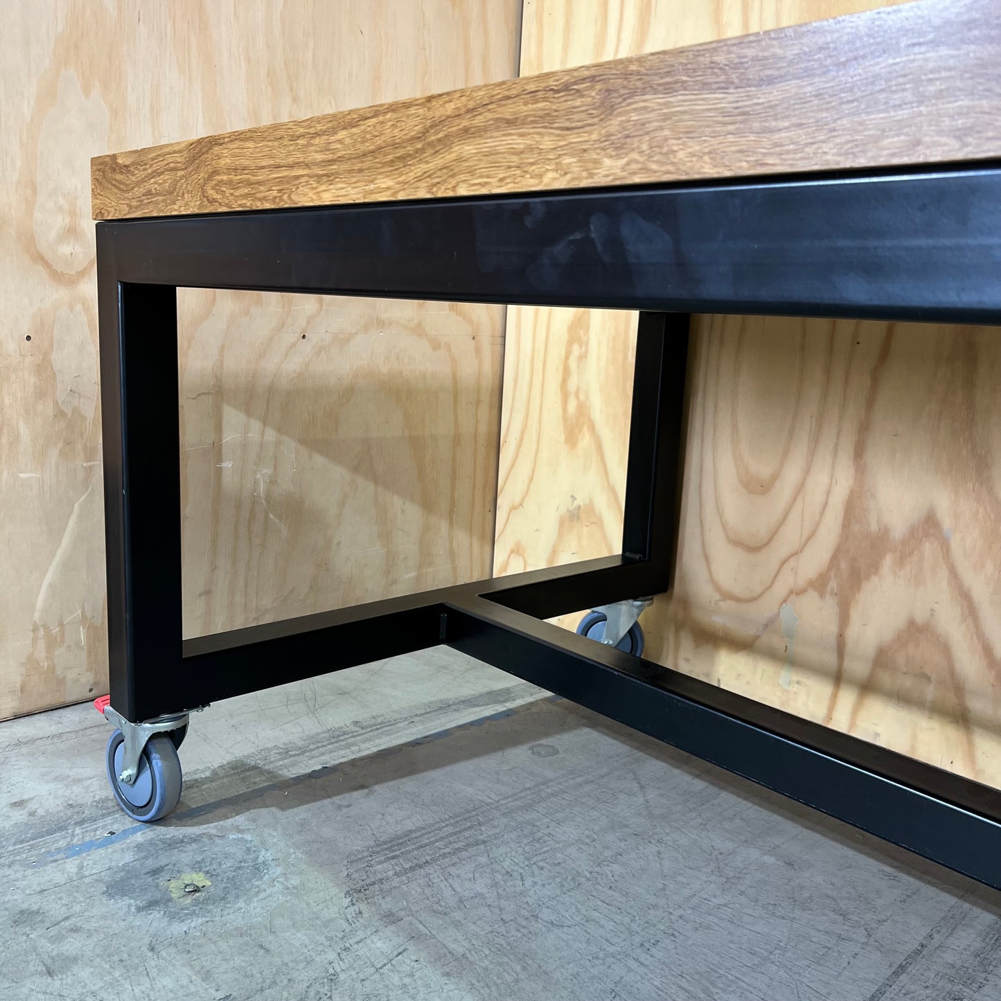 Timber table on black metal frame with castors