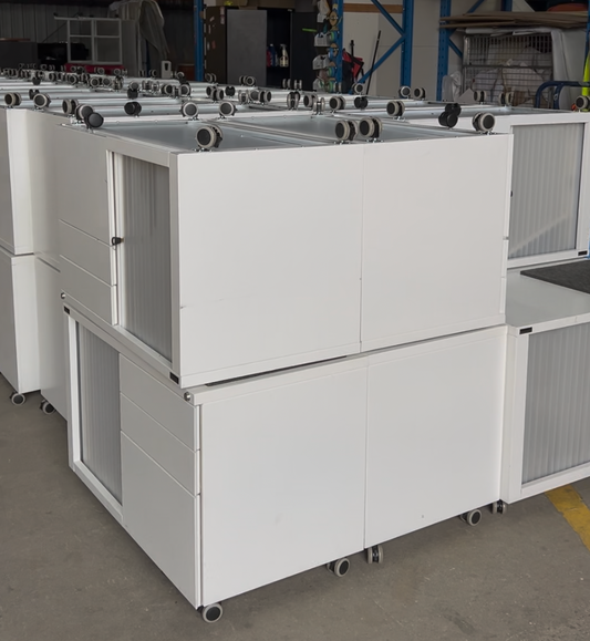 Row of white industrial cabinets with wheels in a warehouse setting