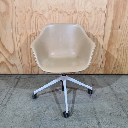 Beige chair with white legs on a wooden floor and concrete floor.