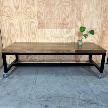 Timber table on black metal frame with castors