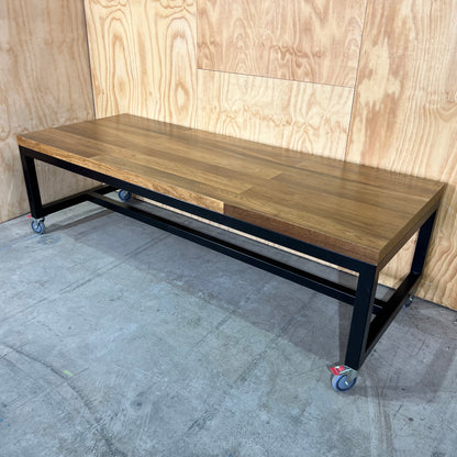 Timber table on black metal frame with castors