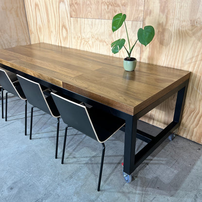 Timber table on black metal frame with castors