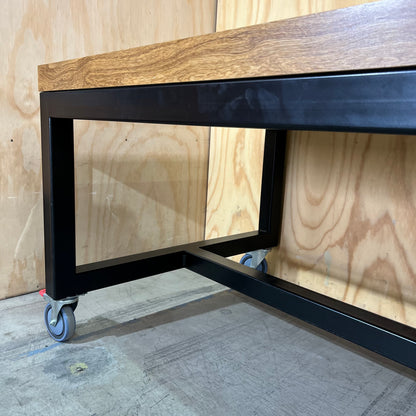 Timber table on black metal frame with castors