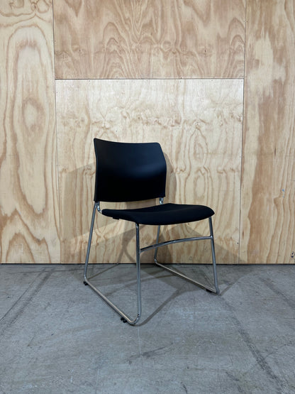 Set of 11 black stackable cushioned chairs with trolley