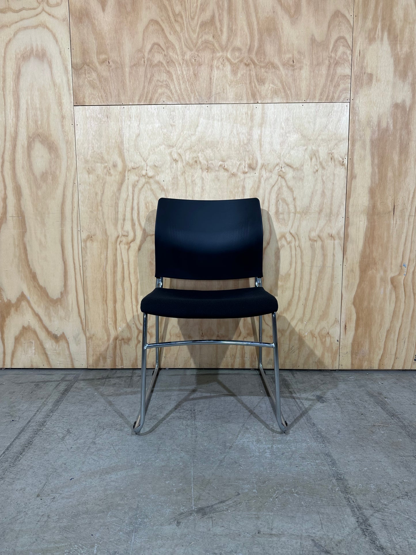 Set of 11 black stackable cushioned chairs with trolley