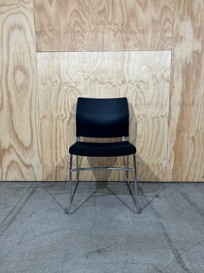 Set of 11 black stackable cushioned chairs with trolley