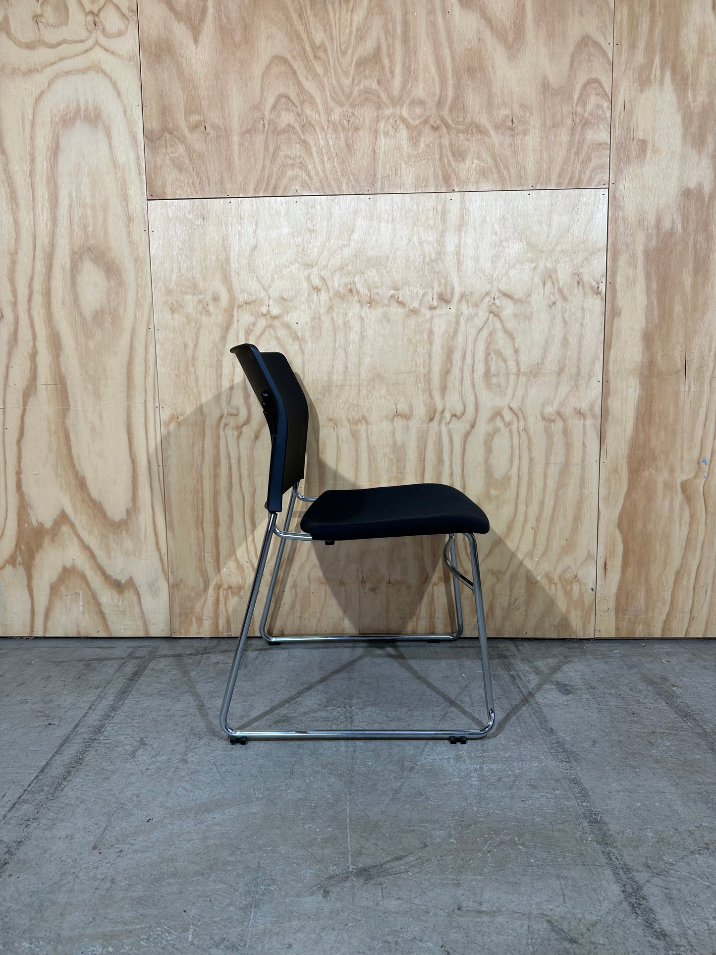 Set of 11 black stackable cushioned chairs with trolley