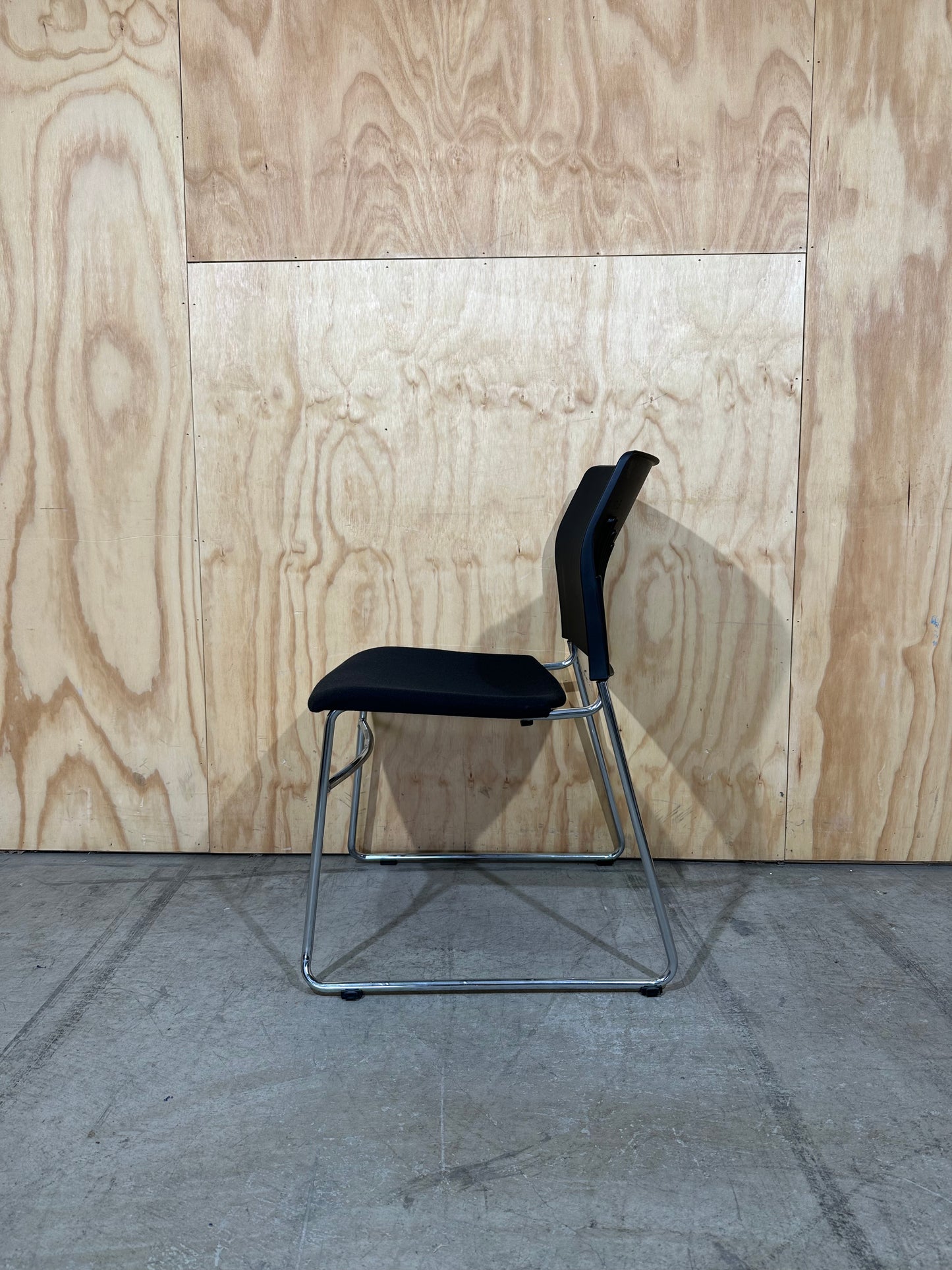 Set of 11 black stackable cushioned chairs with trolley