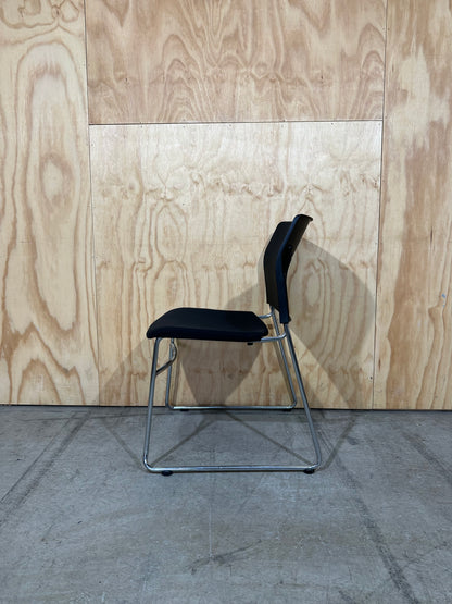 Set of 11 black stackable cushioned chairs with trolley