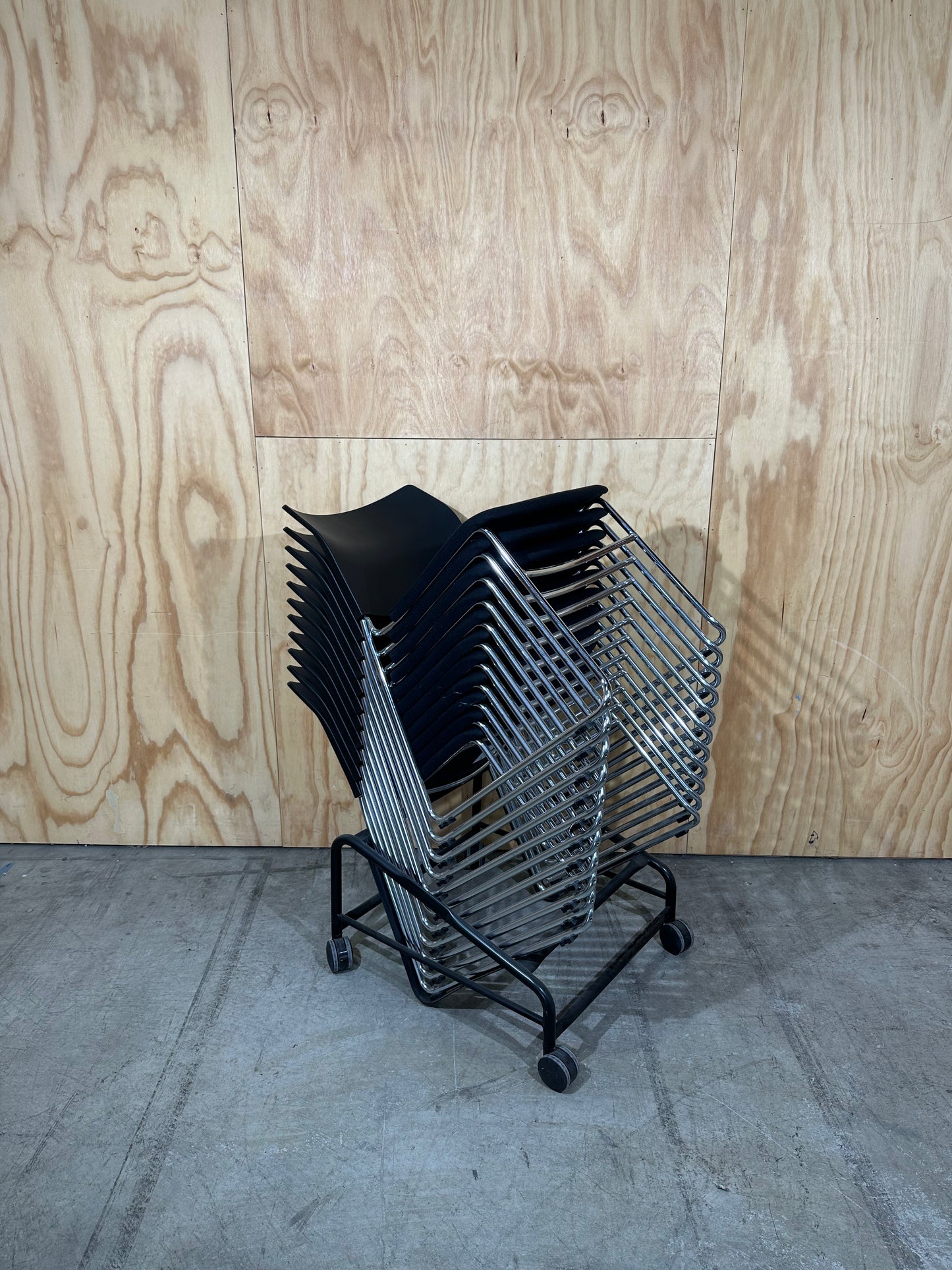 Set of 11 black stackable cushioned chairs with trolley